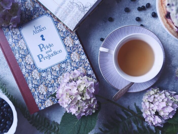 Flat lay of Jane Austen’s Pride and Prejudice book with tea, blueberries, and flowers