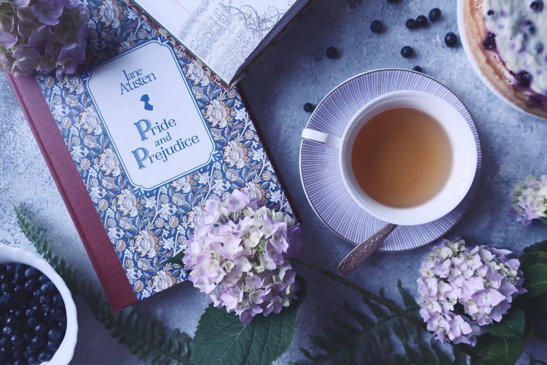Flat lay of Jane Austen’s Pride and Prejudice book with tea, blueberries, and flowers