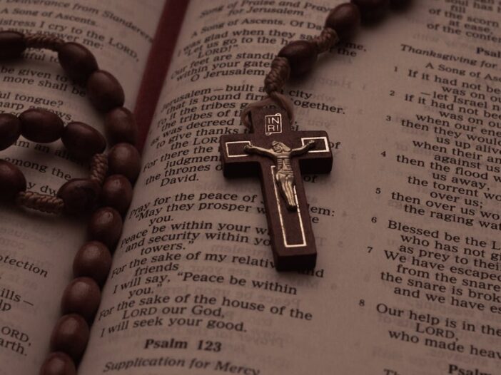 Wooden rosary and crucifix resting on open Bible pages showing Psalms, symbolizing prayer, healing, and spiritual reflection.