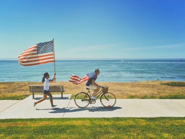 man riding bike and woman running holding flag of USA