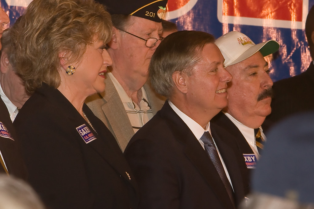 Lindsey Graham smiling, surrounded by veterans and other important people