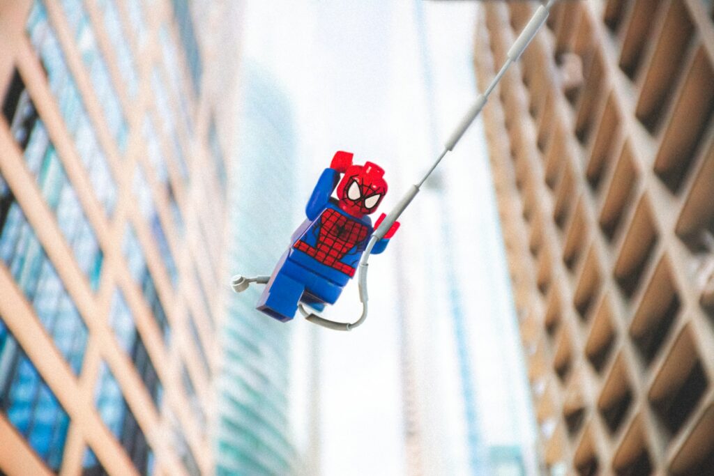 red and blue Spiderman lego toy swinging on web