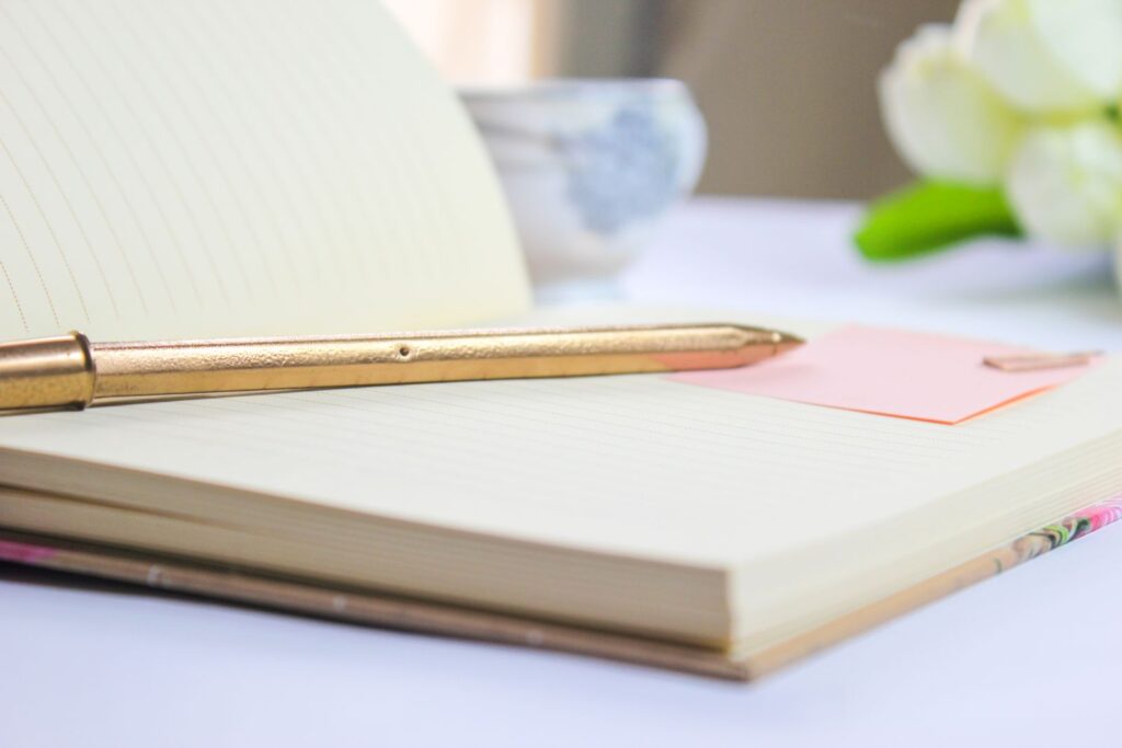 Open notebook with a golden pen and white flowers, perfect for planning and writing ideas.
