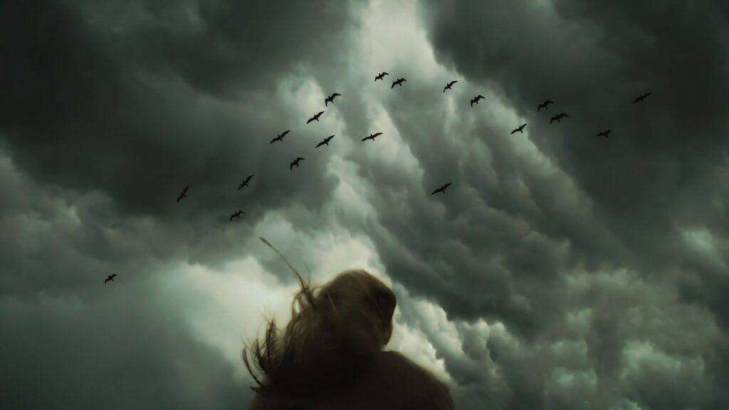 Lone figure watches dark storm clouds, illustrating biblical signs of the end times.