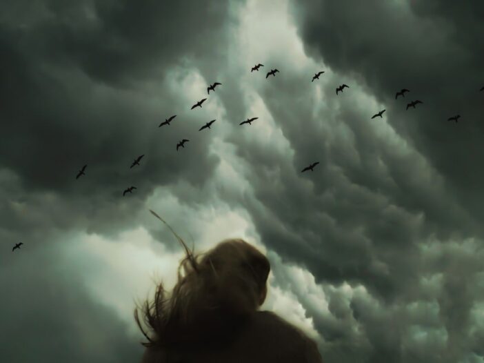 Lone figure watches dark storm clouds, illustrating biblical signs of the end times.