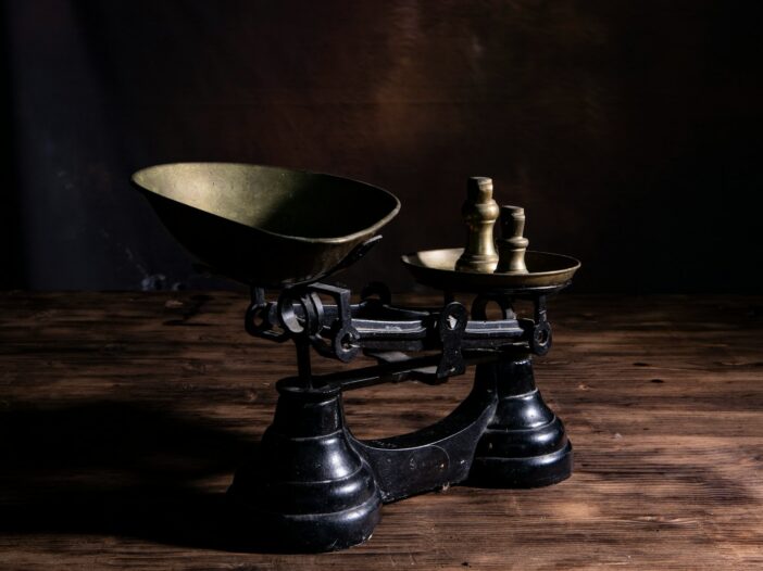 Antique balance scale with uneven weights, illustrating the idea of suicidal empathy and the balance between compassion, judgment, and consequences.
