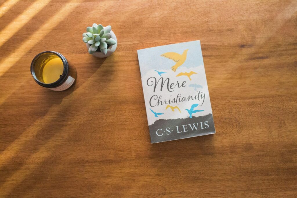 The mere Christianity book by CS Lewis sitting on top of a wooden table next to a cup