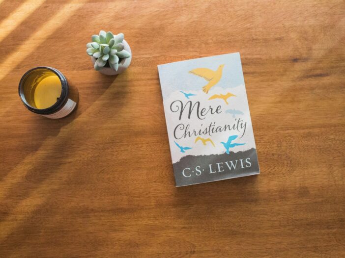 The mere Christianity book by CS Lewis sitting on top of a wooden table next to a cup