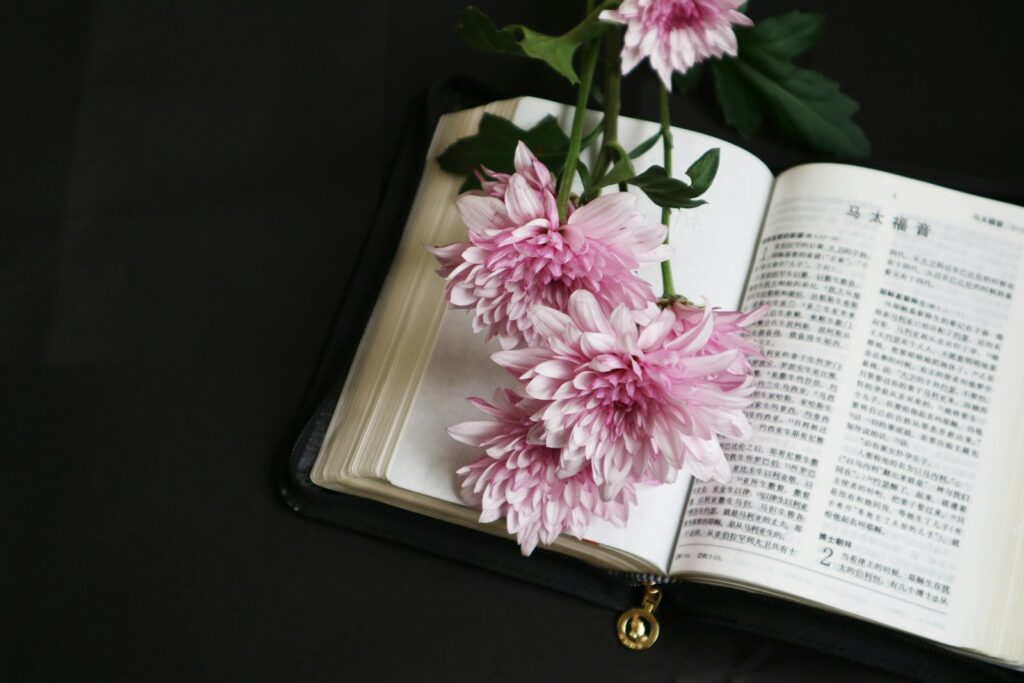Open Bible with pink flowers representing short Bible verses for funeral cards, memorials, and messages of comfort.