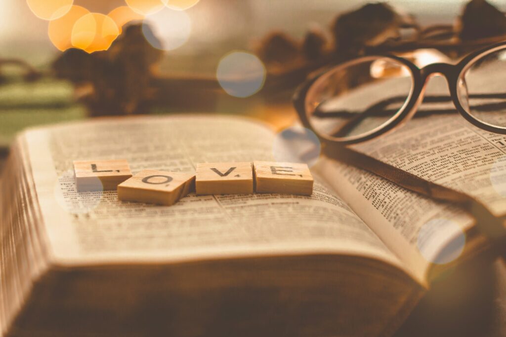 Love scrabble tiles on book page, to illustrate short bible verses about love