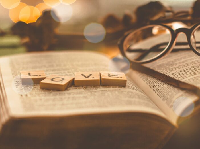 Love scrabble tiles on book page, to illustrate short bible verses about love