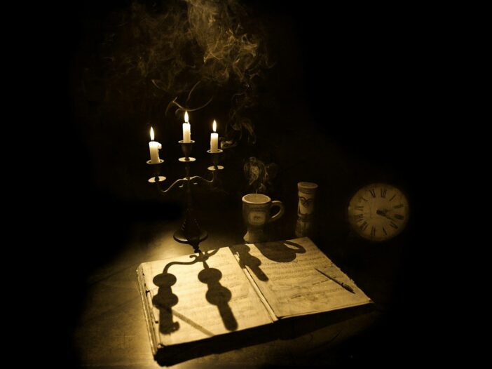 Halloween quotes from literature represented by an antique book, candles, smoke, and clock.