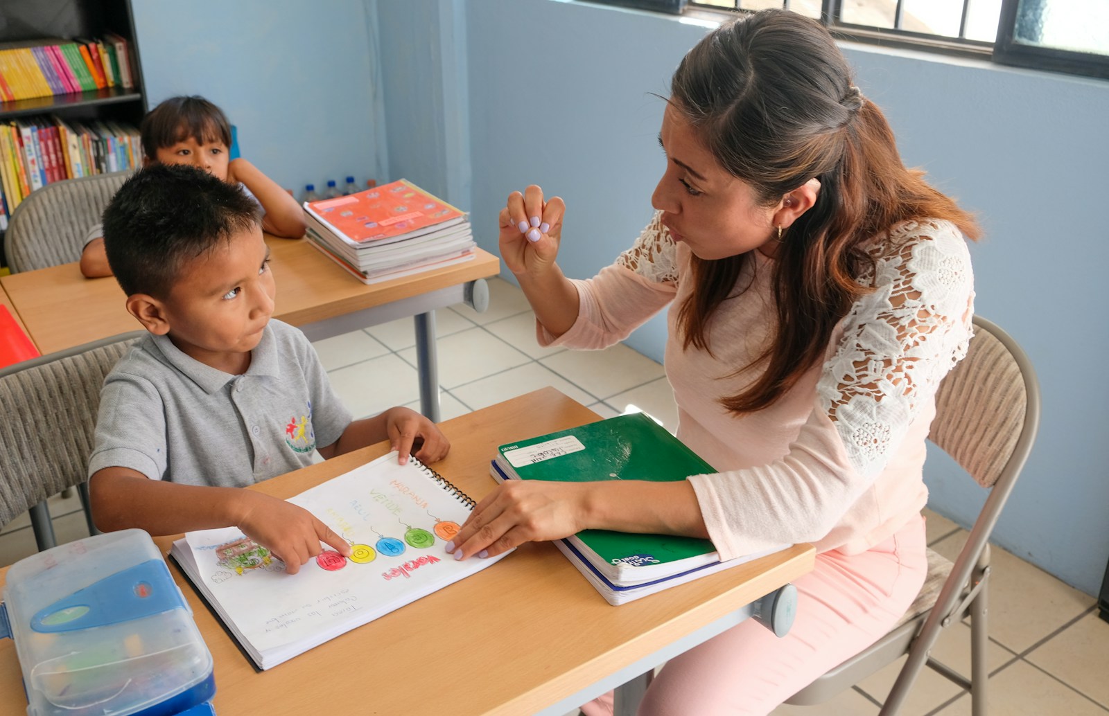 Teacher helping a young student understand a lesson during classroom learning