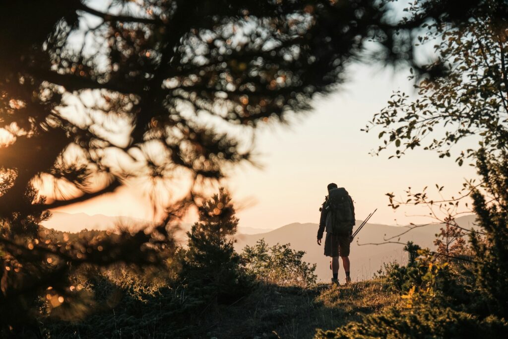 Hiker overlooking a mountain landscape at sunrise, symbolizing courage and trust in the meaning of Joshua 1:9.