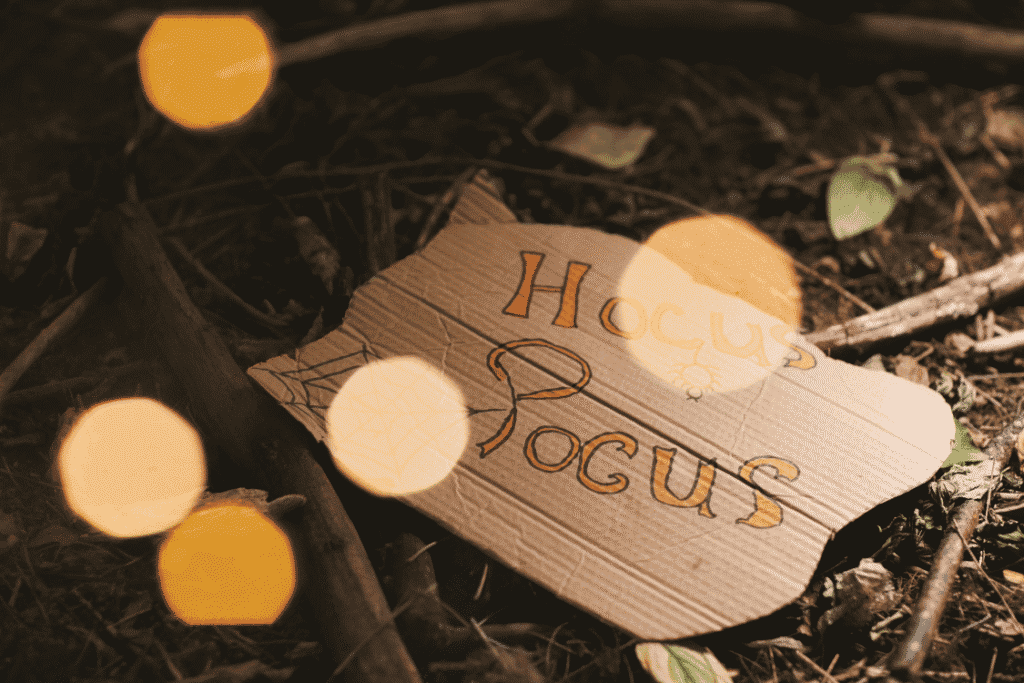 Handmade Hocus Pocus sign resting on the forest floor with warm Halloween lights