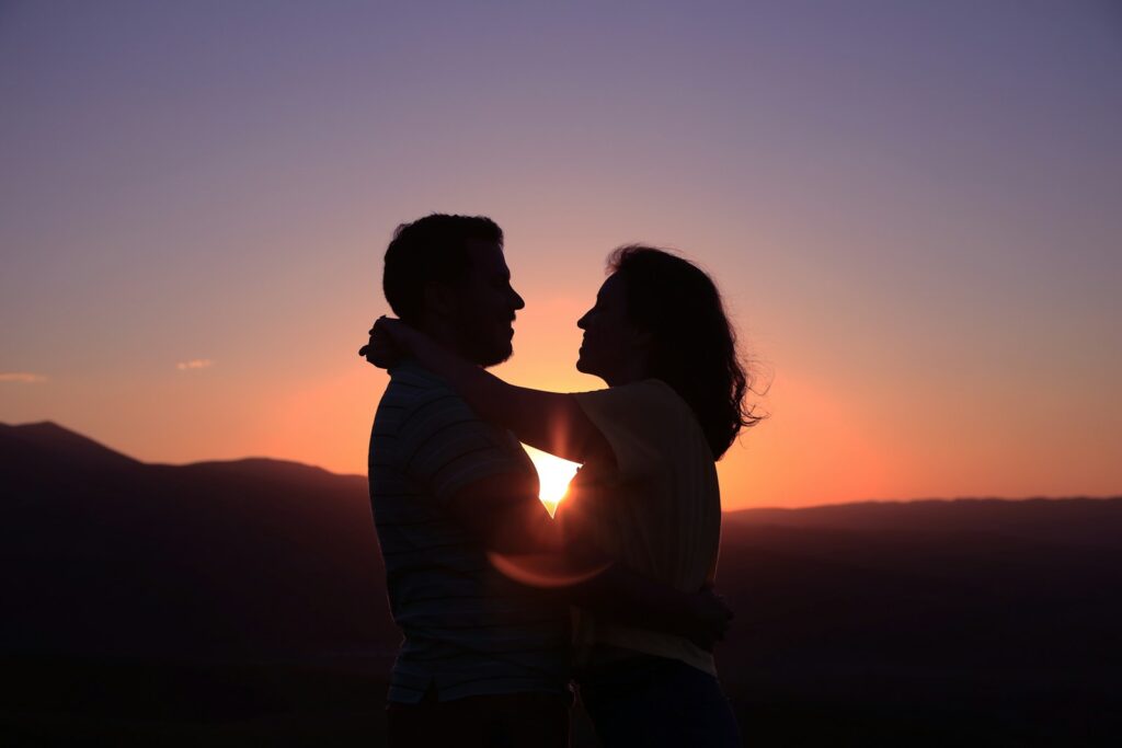 Silhouetted couple embracing at sunset, representing love and committed relationships