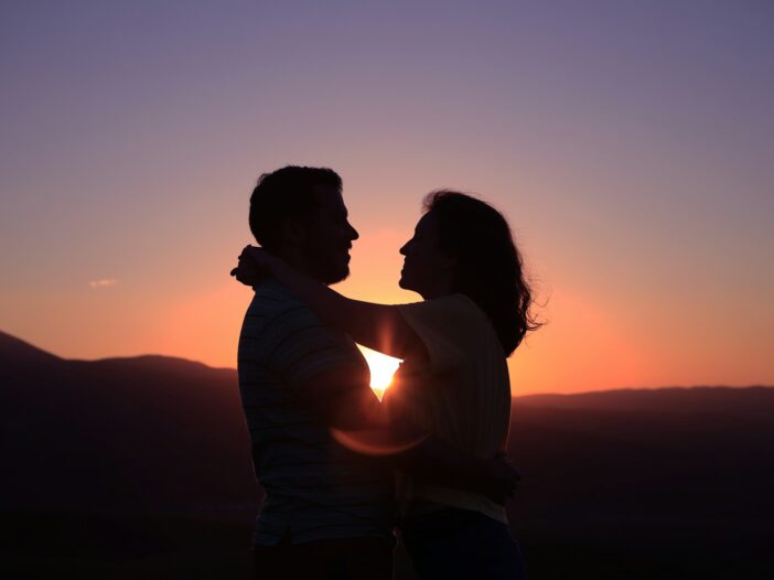 Silhouetted couple embracing at sunset, representing love and committed relationships