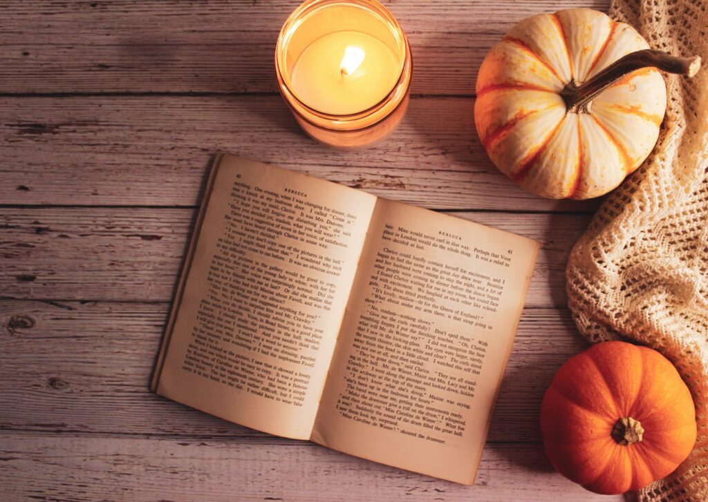 Open book beside pumpkins and a glowing candle for a Thanksgiving poems collection about gratitude and memory.