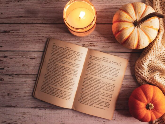 Open book beside pumpkins and a glowing candle for a Thanksgiving poems collection about gratitude and memory.