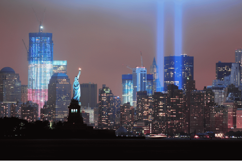 September 11 remembrance lights above Manhattan’s skyline, with the Statue of Liberty in the foreground.