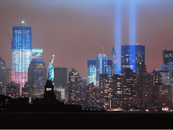 September 11 remembrance lights above Manhattan’s skyline, with the Statue of Liberty in the foreground.