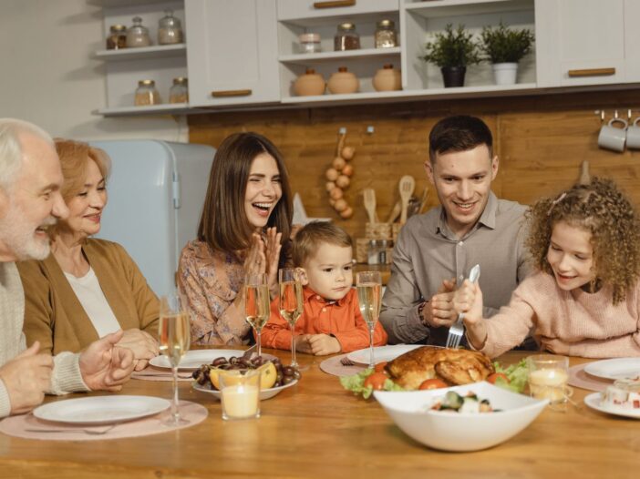 A joyful family gathering around a table for a Thanksgiving feast indoors.