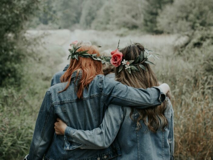 Two friends walking arm in arm outdoors, reflecting the loyal friendship described in Proverbs 17:17.