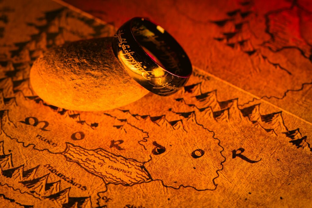 The One Ring resting on a stone above Mordor on a warmly lit Middle-earth map, illustrating lord of the rings quotes.