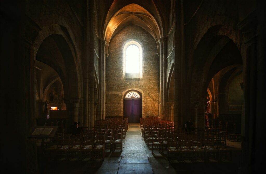 a dimly lit church with rows of chairs, illustrating Churchill's the weight of glory