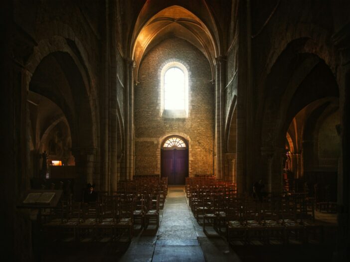 a dimly lit church with rows of chairs, illustrating Churchill's the weight of glory