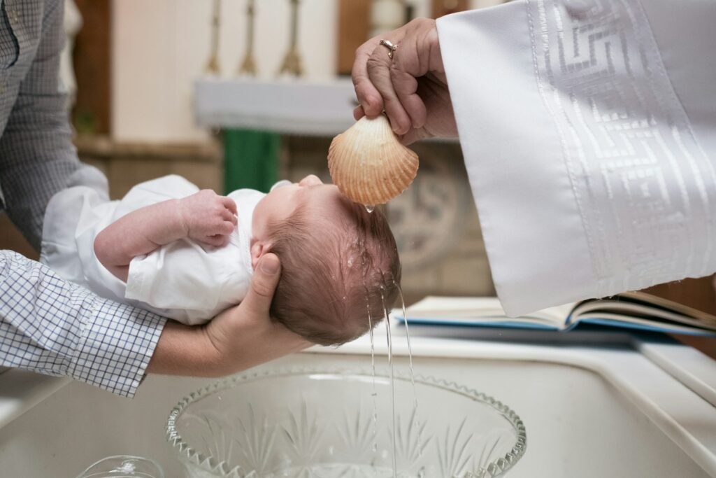 Water poured from a scallop shell over a baby’s head during a church baptism.
