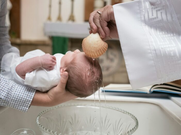 Water poured from a scallop shell over a baby’s head during a church baptism.