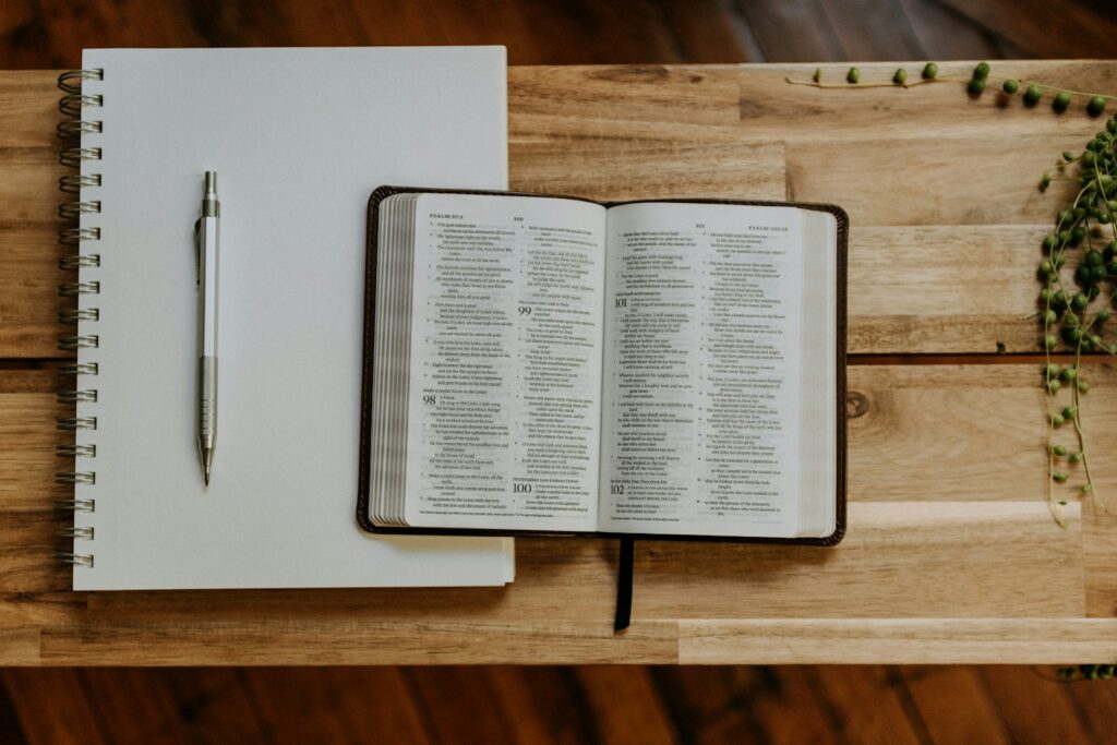 Open Bible beside a notebook and pen, illustrating Colossians 3:23 meaning and wholehearted work.
