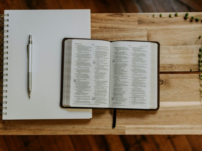 Open Bible beside a notebook and pen, illustrating Colossians 3:23 meaning and wholehearted work.