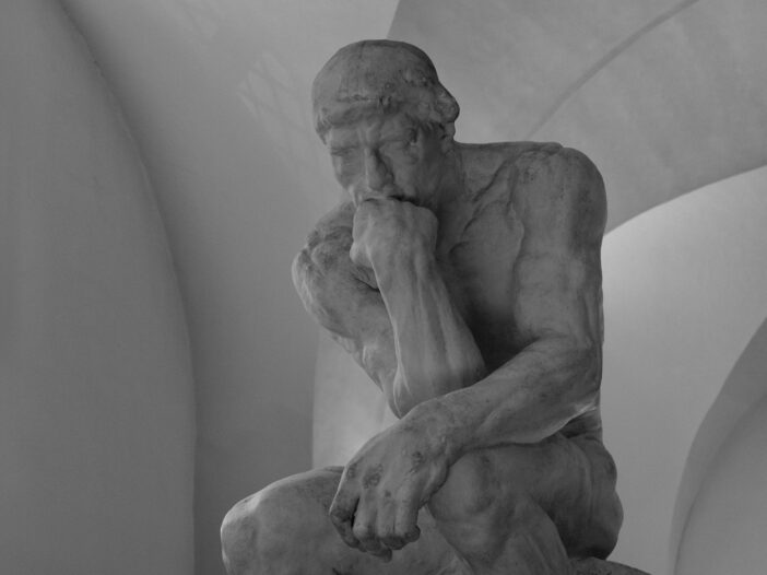 Black-and-white photograph of a seated sculpture resting its chin on one hand in contemplation, illustrating greatest philosophers of all time