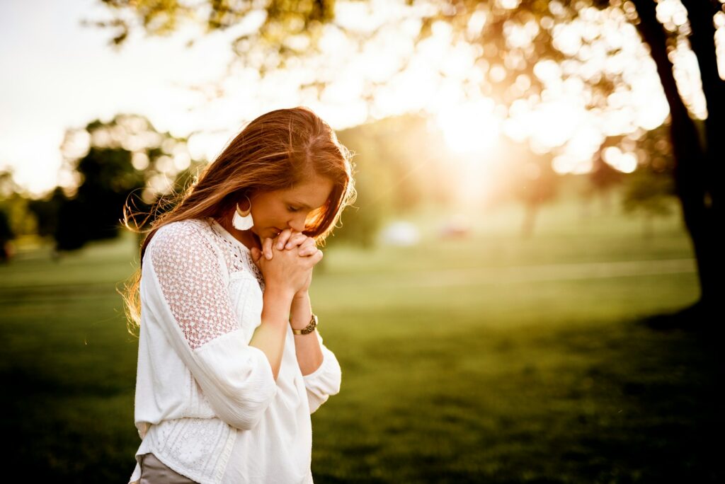 woman praying beside tree with the sun rays in the background, illustrating Hannah's prayer in the Bible
