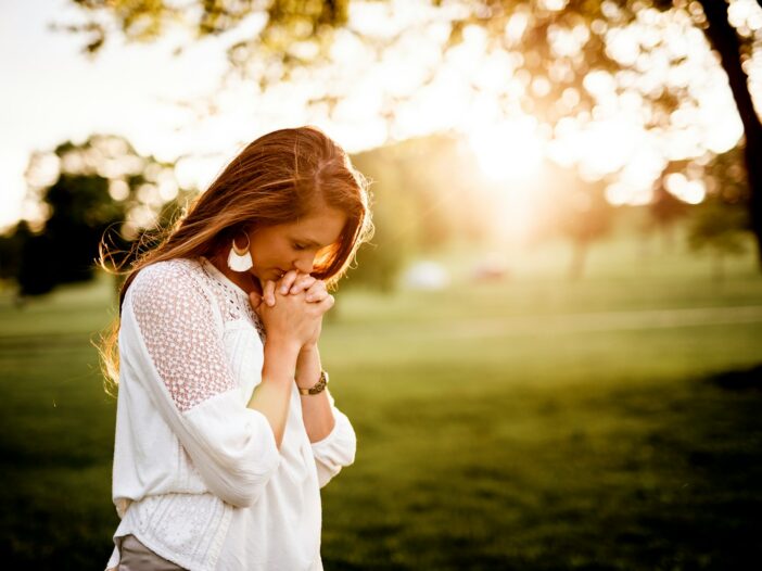 woman praying beside tree with the sun rays in the background, illustrating Hannah's prayer in the Bible