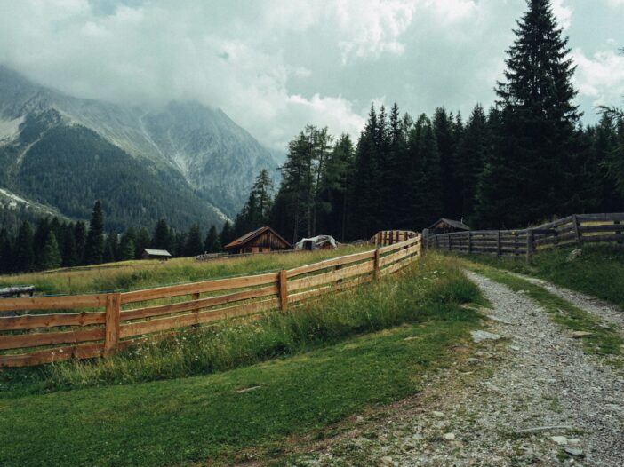 Wooden fence along a gravel path in a mountain meadow