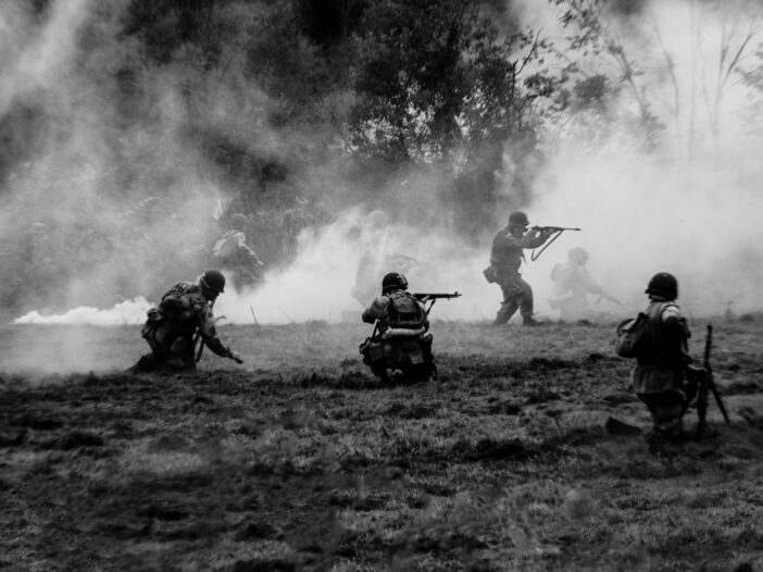 a group of men with guns in a field, illustrating a war movie scene